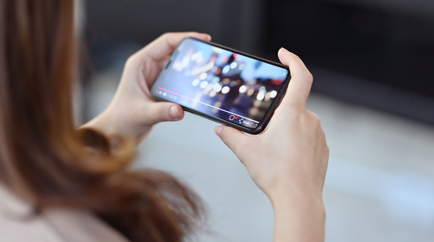 Close-up of a hand holding a contemporary smartphone, finger poised to tap the screen